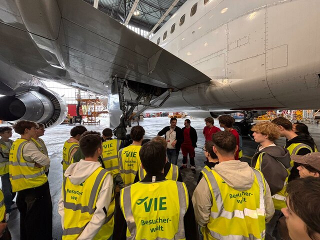Flugzeugtechnik-Schülergruppe am Flughafen Wien-Schwechat, vor einem Flugzeug.