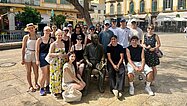 Touristen und eine Statue posieren vor Gebäuden in Neapel, Italien.