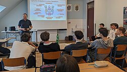 Referent erklärt Schulklasse in einem Klassenzimmer in Österreich die Teamarbeit am Whiteboard.