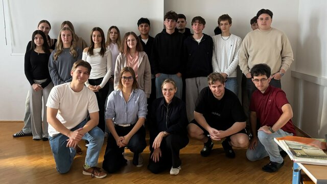 Gruppe von Schülerinnen und Schülern mit Lehrerin in einem Klassenzimmer